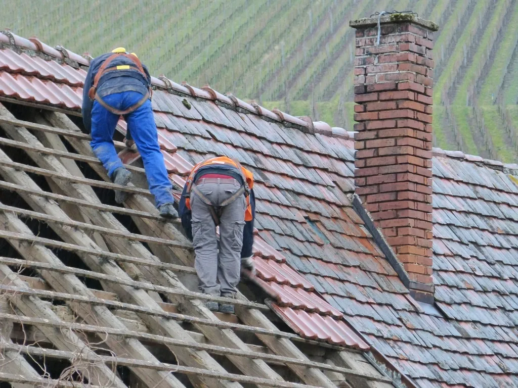 Couvreurs sur une toiture en tuiles en cours de réfection